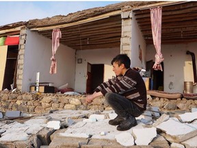 A Turkish child kneels by a destroyed house in Baskale, in the Van province, after a magnitude 5.7 earthquake in northwestern Iran killed at least nine people in neighbouring Turkey and injured dozens more on both sides of the border, authorities said.