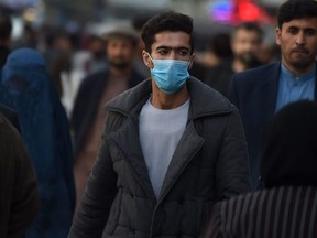 A man wearing a protective facemask walks at the Shahr-i-Naw area in Kabul on February 25, 2020.