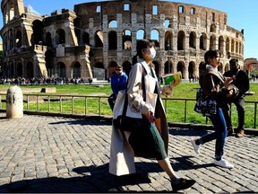 Tourists wearing a protective respiratory mask tour outside the Colosseo monument (Colisee, Coliseum) in downtown Rome on February 28, 2020 amid fear of Covid-19 epidemic.