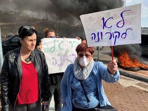 Residents hold placards as they demonstrate against a report that Israel may quarantine visitors from South Korea at a military base in the Jewish settlement of Har Gilo, in the Israeli-occupied West Bank February 23, 2020.