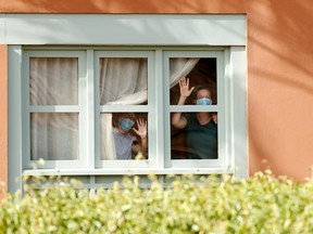 Guests, wearing protective face mask, look through a window at H10 Costa Adeje Palace, which is on lockdown after cases of coronavirus have been detected there in Adeje, on the Spanish island of Tenerife, Spain, February 26, 2020.