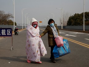 A leukemia patient and her mother coming from Hubei province cross a checkpoint at the Jiujiang Yangtze River Bridge in Jiujiang, Jiangxi province, China, as the country is hit by an outbreak of a new coronavirus, February 1, 2020. (REUTERS/Thomas Peter)