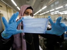An Iraqi worker wears protective face mask following the coronavirus outbreak, as she shows a mask made at a textile factory in Babylon, Iraq February 27, 2020. REUTERS/Essam al-Sudani