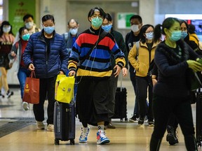 Passengers protective wear face masks as they arrive from Shenzhen to Hong Kong at Lo Wu MTR station hours before the closing of the Lo Wu border crossing in Hong Kong, on Feb. 3, 2020, amid an outbreak of a deadly SARS-like virus which began in the Chinese city of Wuhan.
