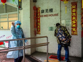 A police officer (L) wearing protective gear gestures as a resident (R) prepares to enter Hong Mei House at Cheung Hong Estate in Hong Kong on Feb. 11, 2020.