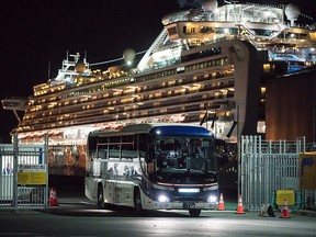 A bus carrying passengers who will take the flight chartered by the government of the Hong Kong Special Administrative Region of the People's Republic of China drives past the quarantined Diamond Princess cruise ship docked the Daikoku Pier on Feb. 19, 2020, in Yokohama, Japan.