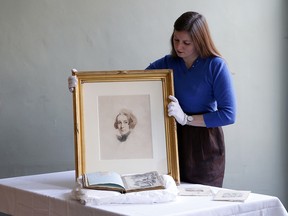 Emma Treleaven holds up the lost third portrait of Charles Dickens by Samuel Laurence on February 7, 2020 in London.  (Hollie Adams/Getty Images)