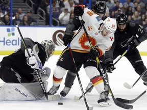 Calgary Flames left wing Andrew Mangiapane battles with Tampa Bay Lightning defenceman Zach Bogosian and centre Blake Coleman for control of the puck in front of goaltender Andrei Vasilevskiy during the first period of an NHL hockey game Saturday, Feb. 29, 2020, in Tampa, Fla.