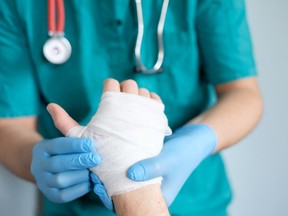 close up of doctor bandaging one hand after an accident