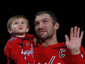 Washington Capitals left wing Alex Ovechkin (8) waves to the crowd with his son Sergei (L) during a ceremony honoring his 700th NHL goal prior to the Capitals' game against the Winnipeg Jets at Capital One Arena on Tuesday.