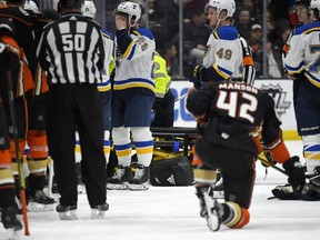 Blues defenceman Vince Dunn, centre, wipes his faces as Ducks defenceman Josh Manson kneels on the ice while Blues defenseman Jay Bouwmeester, who suffered a medical emergency, is worked on by medical personnel during the first period of an NHL game in Anaheim, Calif., on Tuesday, Feb. 11, 2020.