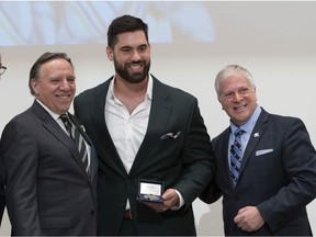 Chiefs' Laurent Duvernay-Tardif receives the National Assembly of Quebec Medal of Honour from Speaker François Paradis, right, while Premier Françcois Legault looks on.