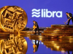 Small toy figures are seen on representations of virtual currency in front of the Libra logo in this illustration picture, June 21, 2019.