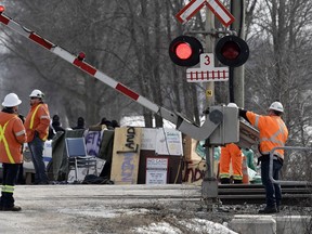 CN Railway workers check the railroad crossing gate as they prepare to resume service after Ontario Provincial Police made arrests at a rail blockade in Tyendinaga Mohawk Territory, near Belleville, Ont., on Monday Feb. 24, 2020.