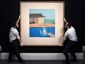 In this file photo taken on February 7, 2020 gallery assistants are pictured posing next to an artwork entitled 'The Splash' 1966, by British artist David Hockney, at Sotheby's Galleries in central London. (DANIEL LEAL-OLIVAS/AFP via Getty Images)