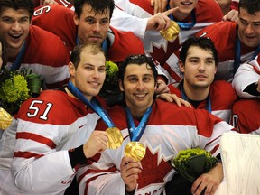 Canada's goaltender Roberto Luongo, centre, and Ryan Getzlaf, left, proudly display their gold medals after defeating the United States 3-2 in overtime in the Olympic men's hockey final in Vancouver on Feb. 28, 2010.