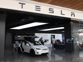 In this file photo taken on April 25, 2019, people stand in a Tesla showroom at a shopping mall in Los Angeles. (MARK RALSTON/AFP/Getty Images)