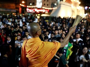 A buddhist monk sprinkles holy water as people pray for victims who died in mass shooting, involving a Thai soldier on a shooting rampage, in Nakhon Ratchasima, Thailand February 9, 2020.