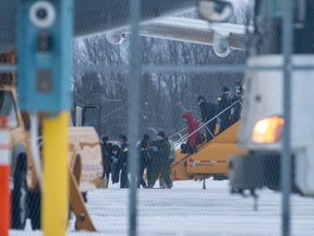 Passengers disembark an airplane carrying Canadian citizens flown out from the coronavirus zone in Wuhan, China, after arriving at CFB Trenton in Trenton, Ont., Canada on Friday, Feb. 7, 2020.