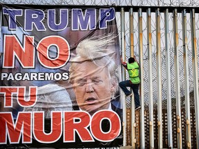 A member of Border Angels hangs a banner reading "Trump we will not pay for your wall" during a demo against him at the US-Mexico border in Playas de Tijuana, Mexico, on February 2, 2020. (GUILLERMO ARIAS/AFP via Getty Images)