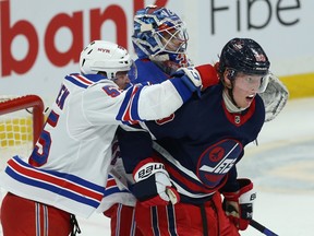 Winnipeg Jets forward Patrik Laine (right) absorbs a shot from New York Rangers defenceman Ryan Lindgren in Winnipeg on Tuessday. Kevin King/Winnipeg Sun/Postmedia Network