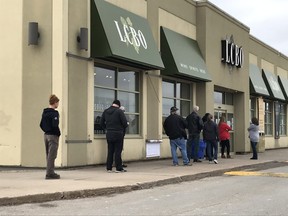 People, practising physical distancing because of the COVID-19 pandemic, line up outside an LCBO outlet in Brantford on March 24, 2020.