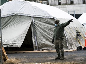 An Air Force member gives instructions as workers and members of the National Guard build a makeshift morgue outside of Bellevue Hospital on March 25, 2020 in New York City.