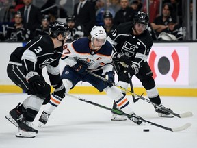 Connor McDavid #97 of the Edmonton Oilers stickhandles the puck between Matt Roy #3 and Anze Kopitar #11 of the Los Angeles Kings during the first period at Staples Center on February 23, 2020 in Los Angeles, California.