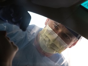 A nurse wearing protective clothing swabs for potential coronavirus at a drive-through testing center at the University of Washington Medical campus on March 13, 2020 in Seattle, Washington. (Photo by John Moore/Getty Images)