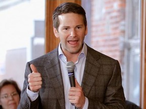 Rep. Aaron Schock (R-IL) (L) tells an audience at Elly's Tea and Coffee why he is endorsing former Republican presidential candidate and former Massachusetts Gov. Mitt Romney (C) during an event with Romney and his wife Ann Romney (R) December 28, 2011 in Muscatine, Iowa.