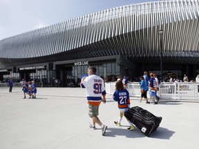 In this Sept. 17, 2017, file photo, hockey fans make their way toward the entrances of the renovated NYCB Live Nassau Coliseum in Uniondale, N.Y., before a preseason NHL hockey game between the New York Islanders and the Philadelphia Flyers.  (AP Photo/Kathy Willens, File)