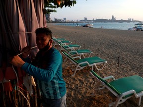 A man collects his umbrellas on an almost empty beach which usually crowed with tourists following the coronavirus disease (COVID-19) outbreak in Pattaya, Thailand March 27, 2020.  (REUTERS/Soe Zeya Tun)