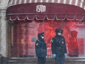 Police officers wearing protective masks stand guard outside the State Department Store, GUM, after the city authorities announced a partial lockdown ordering residents to stay at home to prevent the spread of coronavirus disease (COVID-19), during snowfall in Red Square in central Moscow, Russia March 31, 2020. (REUTERS/Maxim Shemetov)