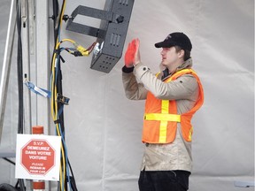 A signaller warms up in a tent as health care workers prepare drive-through COVID-19 at Cavendish Mall in Montreal, March 30, 2020.