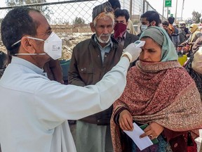 A health personnel checks the body temperature of a pilgrim returning from Iran via the Pakistan-Iran border town of Taftan on February 29, 2020.