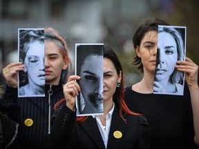 Activists of the "Declic" movement for women's rights hold printed half face pictures showing victims of domestic violence during a protest in Bucharest on March 4, 2020, to draw attention to the lack of monitoring bracelets on the aggressors once a restraining order was issued. (Photo by DANIEL MIHAILESCU/AFP via Getty Images)