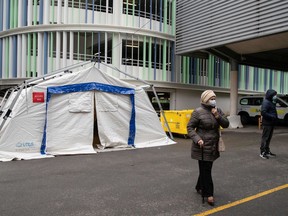 People with COVID-19 symptoms stand outside a tent used as a waiting room set up in a courtyard of the Henri Mondor Hospital in Creteil, near Paris, on March 6, 2020, before having a blood sample taken as the novel coronavirus strain that erupted in China this year and causes the COVID-19 disease already left nine dead in France and made hundreds ill.