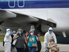 A woman gestures as medical personnel help load passengers from the Grand Princess cruise ship onto airplanes at Oakland International Airport in Oakland, California on March 10, 2020.