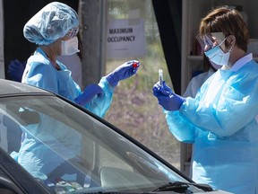 Medical workers at Kaiser Permanente French Campus test a patient for the novel coronavirus, COVID-19, at a drive-thru testing facility in San Francisco, California on March 12, 2020.