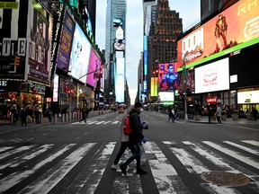 People wearing masks cross the street in Times Square in Manhattan on March 17, 2020 in New York City.