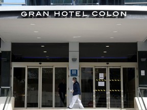 A health worker wearing a face mask enters the Gran hotel Colon in Madrid, a first hotel that was transformed into a medical structure to treat the least serious cases amid the outbreak caused by the novel coronavirus, on March 19, 2020.