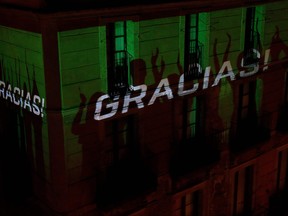 The shadows of residents are reflected on a building reading "Gracias" in Barcelona on March 21, 2020 as people go to their balconies and windows every day to applaud and cheer the healthcare workers dealing with the new coronavirus crisis. (PAU BARRENA/AFP via Getty Images)