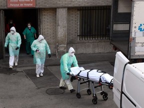 A health worker carries a body on a stretcher outside Gregorio Maranon hospital in Madrid on March 25, 2020.