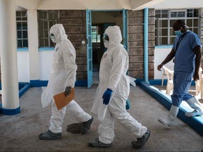 Laboratory specialists wearing protective gear walk toward the ward for quarantined people who had close contacts with the first Kenyan patient of the COVID-19 at Kenyatta National Hospital in Nairobi, Kenya, on March 15, 2020. (YASUYOSHI CHIBA/AFP via Getty Images)