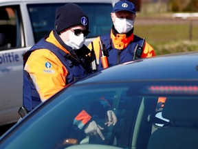 Belgian police officers wearing protective masks control a driver on the Belgian-Dutch border during the coronavirus lockdown in Meersel-Dreef, Belgium March 25, 2020. (REUTERS/Francois Lenoir/File Photo)