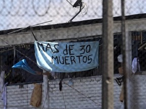 A sign hanged by inmates reading 'More than 30 dead' is seen after a riot at the Modelo prison in Bogota, Colombia, Sunday, March 22, 2020.