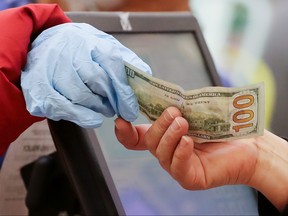 A woman pays cash while wearing gloves at Northgate Gonzalez Market on March 19, 2020 in Los Angeles. (Mario Tama/Getty Images)