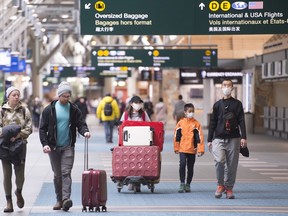 Travellers are seen at Vancouver International Airport in Richmond, B.C. Friday, March 13, 2020. The Canada Border Services Agency says it is adding new screening questions for travellers arriving in Canada, asking whether they have symptoms of COVID-19.