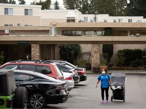 A worker carries a garbage can while wearing a mask at the Life Care Center of Kirkland, where two of three confirmed coronavirus cases in the state had links to the long-term care facility in Kirkland, Washington, U.S. March 1, 2020.