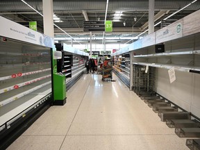A shopper walks past empty milk and dairy shelves amidst the COVID-19 pandemic in Manchester, England on March 20, 2020. (OLI SCARFF/AFP via Getty Images)